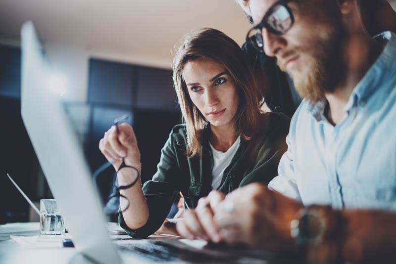 A man and woman look intensely at their computer while making big marketing plans